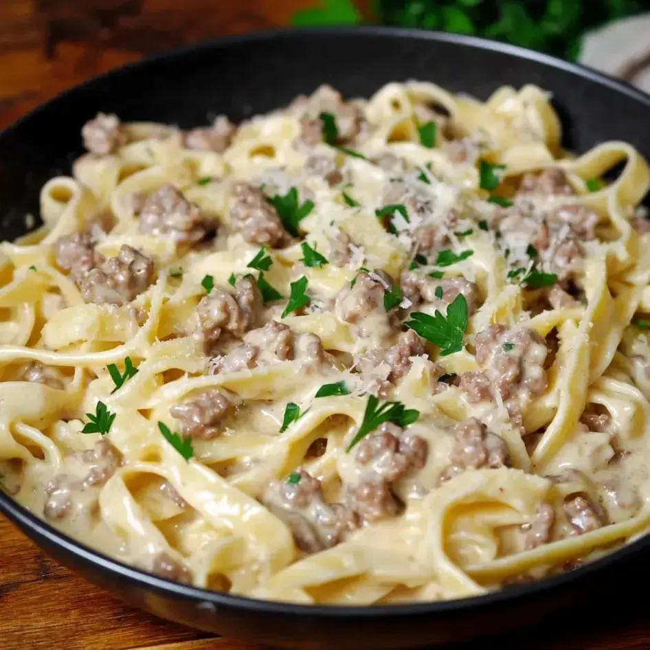 Eine Schüssel cremige Fettuccine-Pasta mit Hackfleisch und Petersilie garniert.