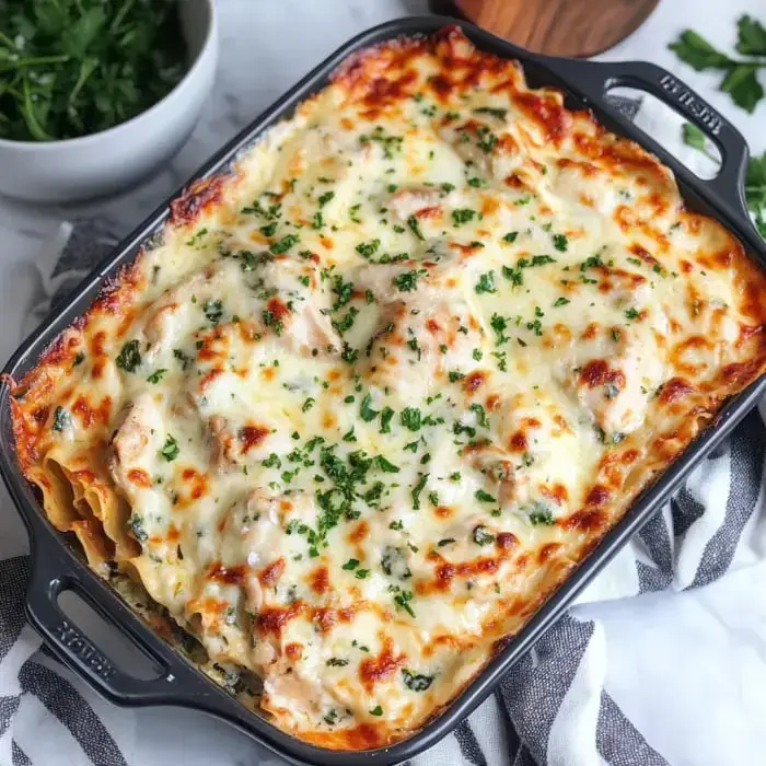 Eine gebackene Lasagne mit geschmolzenem Käse überbacken und mit Petersilie garniert, serviert in einer schwarzen Auflaufform.