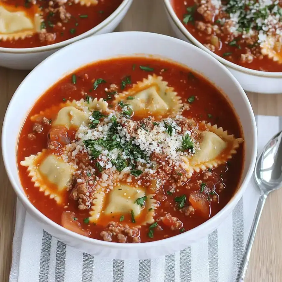 Eine Schüssel Ravioli-Suppe mit Fleisch, Tomatensoße und garniert mit Petersilie und geriebenem Käse.