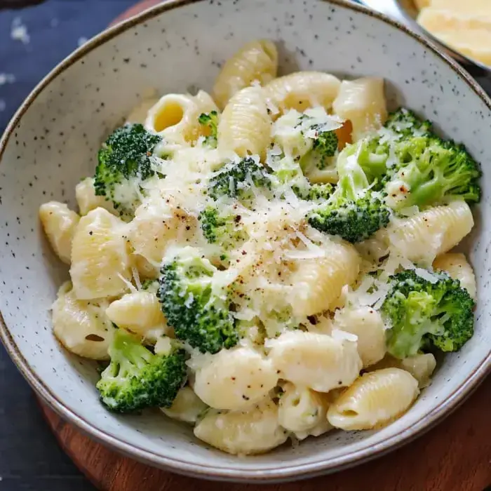 Eine Schüssel cremige Pasta vermischt mit Brokkoli und mit geriebenem Käse bestreut.