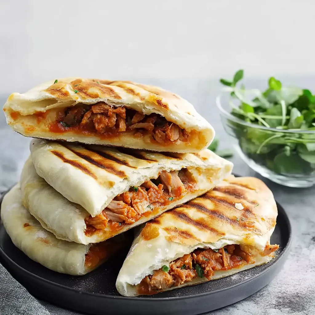 Eine Platte mit Sandwiches, die mit Käse und Sauce garniert sind.