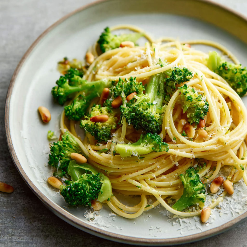 A plate of spaghetti with broccoli and pine nuts.