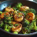 A pan of shrimp and broccoli with a spicy sauce.