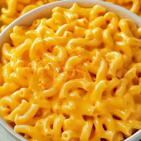Eine Nahaufnahme einer Schüssel mit cremigen Makkaroni mit Käse, bestreut mit Paprikapulver.