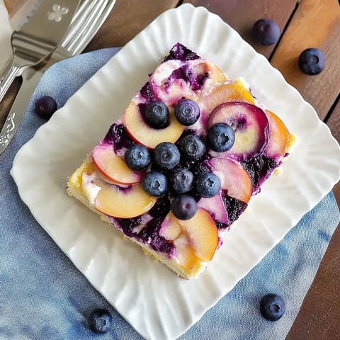 Eine Schokoladencake mit einer Schicht aus Apfel und Blaubeeren auf einem weißen Platter.
