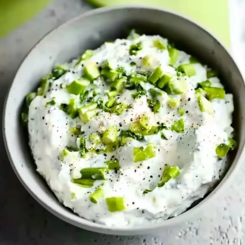 Ein weißer Käsekratzer mit grünen Zwiebeln und Kräutern.