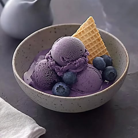 Ein Glas mit Purpur-Eiscreme und Wacholderkrumen.