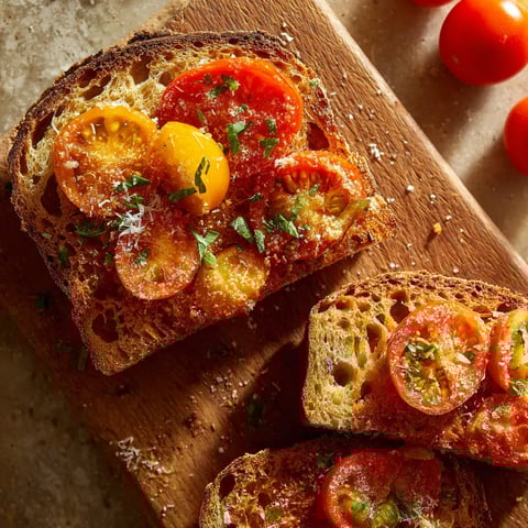Eine Scheibe Toast mit Tomaten und Basilikum darauf.