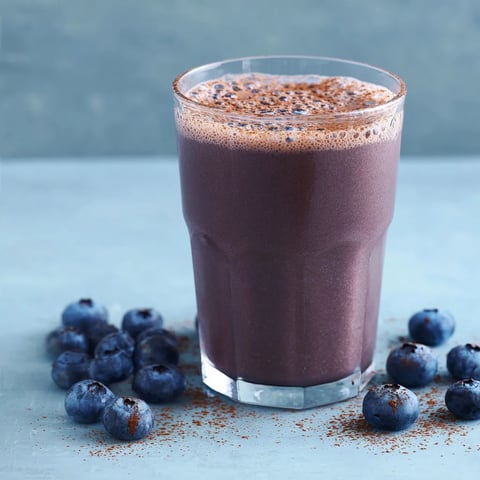 Ein Glas mit Schokolade und Blaubeeren auf einem Tisch.