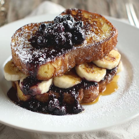 A stack of French toast with blueberries on top.