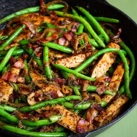 A pan of food with green beans and bacon.