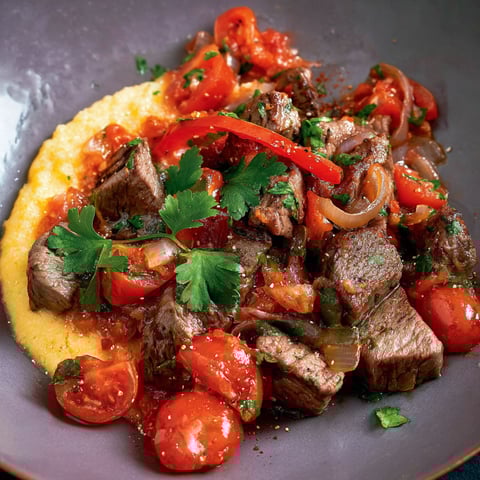 A plate of meat with tomatoes and onions.
