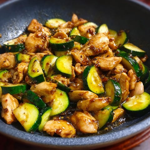 A bowl of chicken and zucchini.