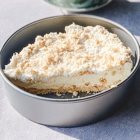 A cream filled pastry with coconut on top.