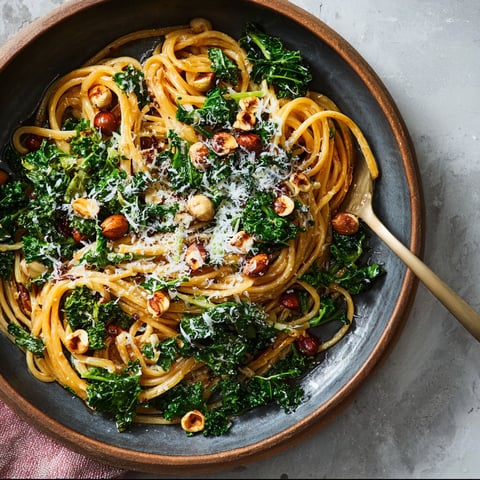 A bowl of pasta with broccoli, nuts, and spinach.