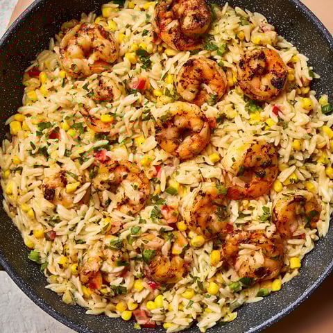 A pan of rice with shrimp and corn.