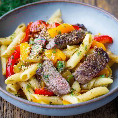 A bowl of pasta with meat and peppers.