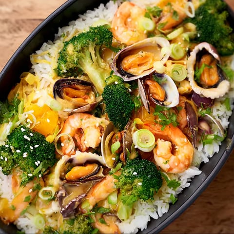 A bowl of food with shrimp, rice, and broccoli.