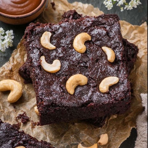 A square of vegan brownies with nuts on top.