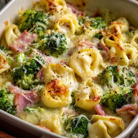 A dish of tortellini with broccoli and ham.